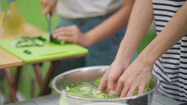 Hands preparing vegetables and herbs on a cutting board